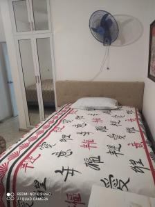 a bed with chinese writing on it with a fan at Sweet beach apartment in San Felipe de Puerto Plata