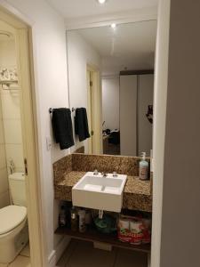 Un baño con lavabo, inodoro y espejo. en Flat 519, en Macaé