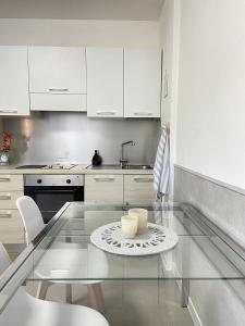 a kitchen with a glass table and white cabinets at Monolocale vicino Pordenone Fiera  +4 photos
