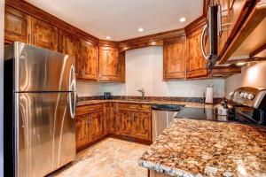 a kitchen with wooden cabinets and a stainless steel refrigerator at Ski Hill 15 by Ski Country Resorts in Breckenridge