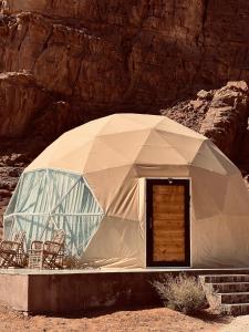 a tent with chairs and a door in the desert at RUM MARS lUXURY CAMP in Wadi Rum
