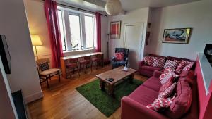 a living room with a red couch and a table at A Baronial Hall apartment - great views of Loch Fyne 