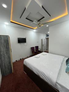 a hotel room with a bed and a flat screen tv at HR Guest House in Gilgit