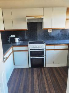 een keuken met witte kasten en een fornuis bij Woodside room Glasgow in Glasgow
