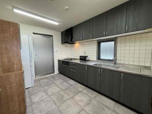 een keuken met zwarte kasten en een spoelbak bij Ocean View Mt, Kaimondake - Vacation STAY 58439v in Oka-chiyogamizu