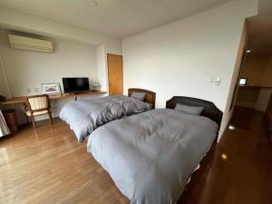 een slaapkamer met 2 bedden en een bureau met een televisie bij Ocean View Mt, Kaimondake - Vacation STAY 58439v in Oka-chiyogamizu