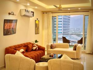 a living room with couches and chairs and a large window at High Rise Presidential Suite in Elysium Opp Centaurus in Islamabad