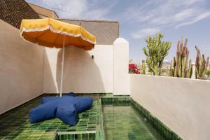 un patio con sombrilla y piscina en Riad La Lumière d'Étoile, en Marrakech