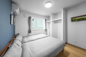 a white bedroom with a bed and a window at Charmant House III - Vacation STAY 20373 in Minamifurano