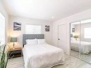 a white bedroom with a large bed and a mirror at Sunny Studio in the Heart of Venice - A in Los Angeles
