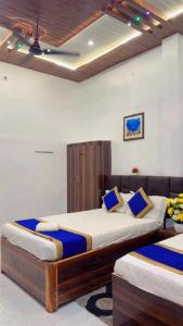 a bedroom with two beds with blue pillows at Hotel shree ji palace in Pāldhi