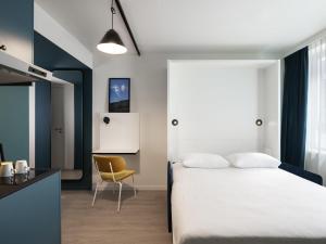 Un dormitorio con una cama blanca y una silla amarilla. en Adagio Access Gent Centrum Dampoort, en Gante