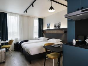 Una habitación de hotel con una cama, una mesa y sillas. en Adagio Access Gent Centrum Dampoort, en Gante 77 fotos más