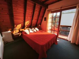 a bedroom with a bed with a red blanket and a window at Alpino Mitre in Mar de Ajó