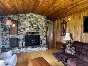 a living room with a stone fireplace and couches at Cozy Farmhouse B&B Retreat in Williams Lake