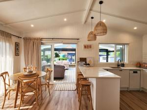 a kitchen and living room with a table and chairs at Seashell Cottage Hahei in Hahei