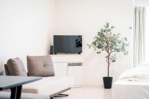 ein weißes Wohnzimmer mit einer weißen Couch und einem Baum in der Unterkunft Greenfield - Vacation STAY 20427 in Hayaki