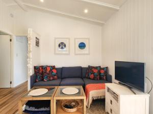 a living room with a blue couch and a tv at Seashell Cottage Hahei in Hahei