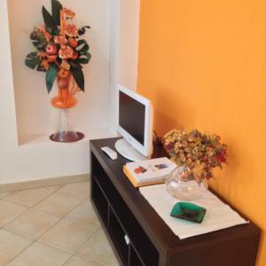 - un bureau avec un moniteur d'ordinateur et un vase de fleurs dans l'établissement Palazzo Russo, à Ribera