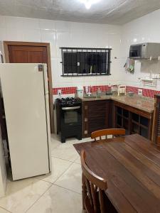 une cuisine avec une table en bois et un réfrigérateur blanc dans l'établissement Loft da Praia dos Corais, à Cabo Frio