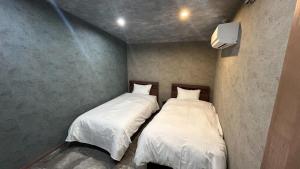 two beds in a small room with white sheets at Tabinoteitaku BREATHTAKEMatsushima - Vacation STAY 66188v in Takagi