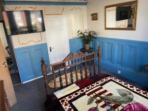 a room with a bed with blue walls and a mirror at PERiVALE LODGE in Folkestone