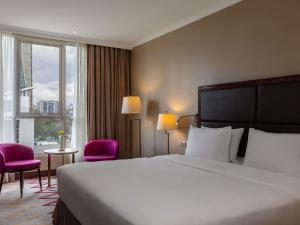 een hotelkamer met een groot bed en twee roze stoelen bij Mercure Nairobi Upper Hill in Nairobi