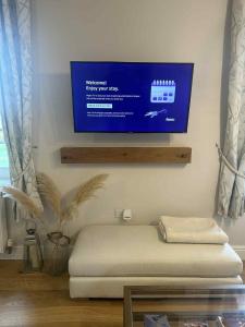 a room with a bed with a tv on the wall at Luxury 1 Bedroom Flat in Great Location in Bicester