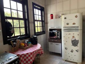 a kitchen with a table and a white refrigerator at Casa do Guia - Casa compartilhada in Ouro Preto