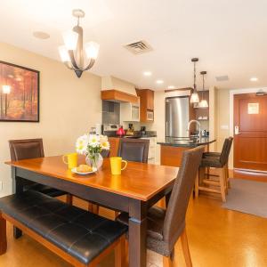 a kitchen and dining room with a wooden table and chairs at Mountain Bliss Spacious 2BR with Pool and Hot Tub in Canmore