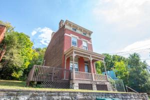 a red brick house with a balcony on the front at Queen City Suites 1 - For 3 in Cincinnati
