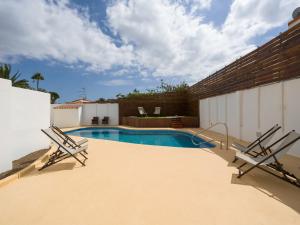 a swimming pool with two chairs next to a building at Florida Home Private pool and Jacuzzi in San Bartolomé