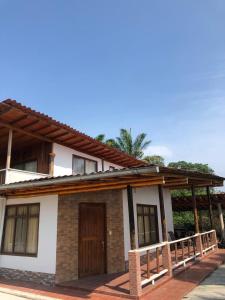 een klein wit huis met een houten deur bij Alma y Palma Casa Campestre in Pedro Vicente Maldonado