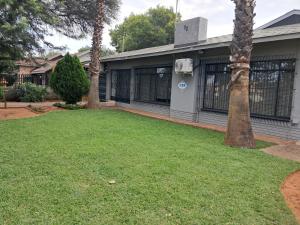 a yard with two palm trees in front of a house at Greenfield in Klerksdorp