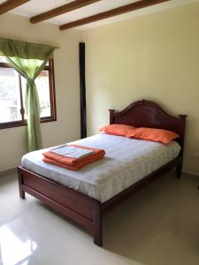 een slaapkamer met een bed met oranje kussens en een raam bij Alma y Palma Casa Campestre in Pedro Vicente Maldonado