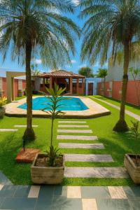 a swimming pool with palm trees in front of a house at Pousada Mazé in Itanhaém +22 photos