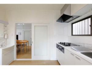 eine weiße Küche mit einem Waschbecken und einem Tisch in der Unterkunft LIFE TOWN NISHIROKUGO - Vacation STAY 20474 in Tokio