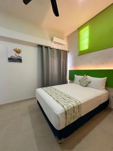 une chambre avec un grand lit avec un mur végétal dans l'établissement Deptos Modernos Colonia México, à Mérida