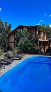 a large blue swimming pool in front of a house at Pousada Aimê Maresias in São Sebastião