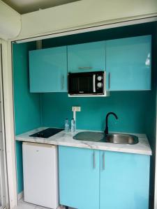 cocina azul con fregadero y microondas en La Galante, studio proche plage privée, en Grand-Bourg