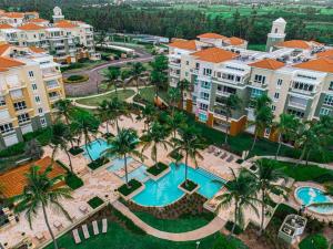 an aerial view of a resort with a pool and palm trees at Coastal Living With Golf Course Vistas Otium in Humacao