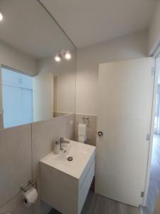Un baño blanco con lavabo y espejo. en Quark Apartments, en Lima 28 fotos más