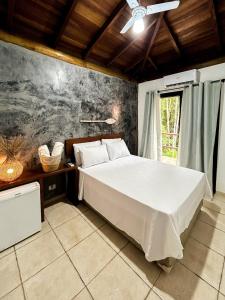 a bedroom with a large white bed in a room at Pousada Aimê Maresias in São Sebastião