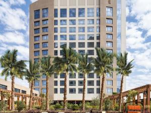a tall building with palm trees in front of it at Movenpick Hotel and Residences Riyadh in Riyadh
