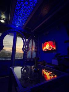 Una habitación con chimenea y una ventana con televisión. en DAR AMRANi, en Chefchaouen