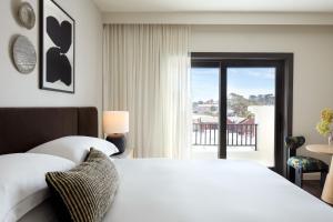 Un dormitorio con una cama blanca y un balcón. en Kimpton Mirador Pacific Grove Monterey by IHG, en Pacific Grove