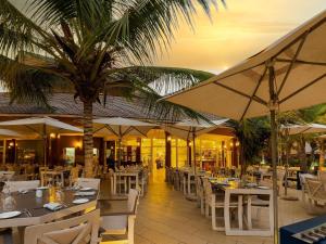 a restaurant with tables and umbrellas and a palm tree at Movenpick Resort Lamantin Saly in Saly Portudal