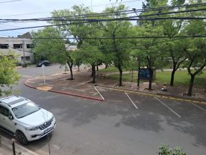 a white car parked in a parking lot with trees at la piazza in La Porteña