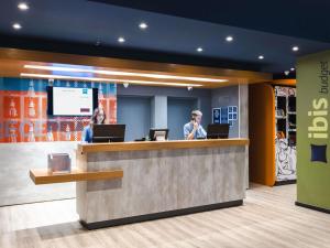 two people standing at a counter in a lobby at ibis budget Pindamonhangaba in Pindamonhangaba