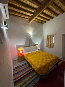 a bedroom with a yellow bed in a room at Riad Dar Zaouia in Zagora